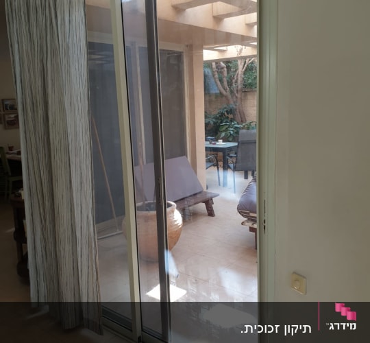 דלת זכוכית הזזה עם וילון בצד ימין